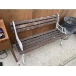 A WOODEN SLATTED GARDEN BENCH WITH DECORATIVE CAST BENCH ENDS