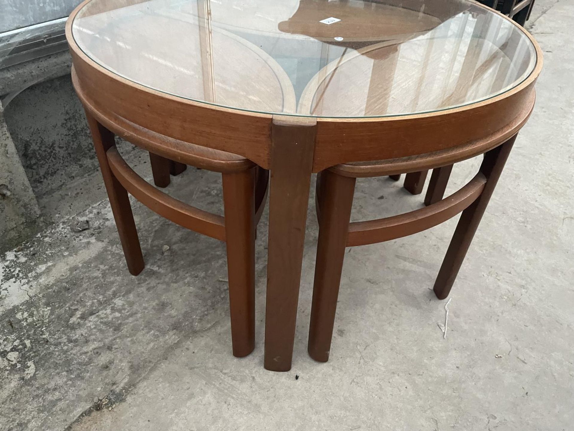 A RETRO TEAK CIRCULAR NEST OF FOUR TABLES WITH GLASS TOP AND THREE UNDER TABLES, OVAL IN SHAPE, - Image 3 of 7