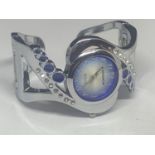 A CANSOW FASHION WATCH ON A WHITE METAL A BANGLE STRAP WITH CLEAR AND BLUE STONE DECORATION SEEN