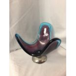 A PURPLE AND TURQUOISE GLASS ABSTRACT DESIGN DISH ON A WHITE METAL STAND