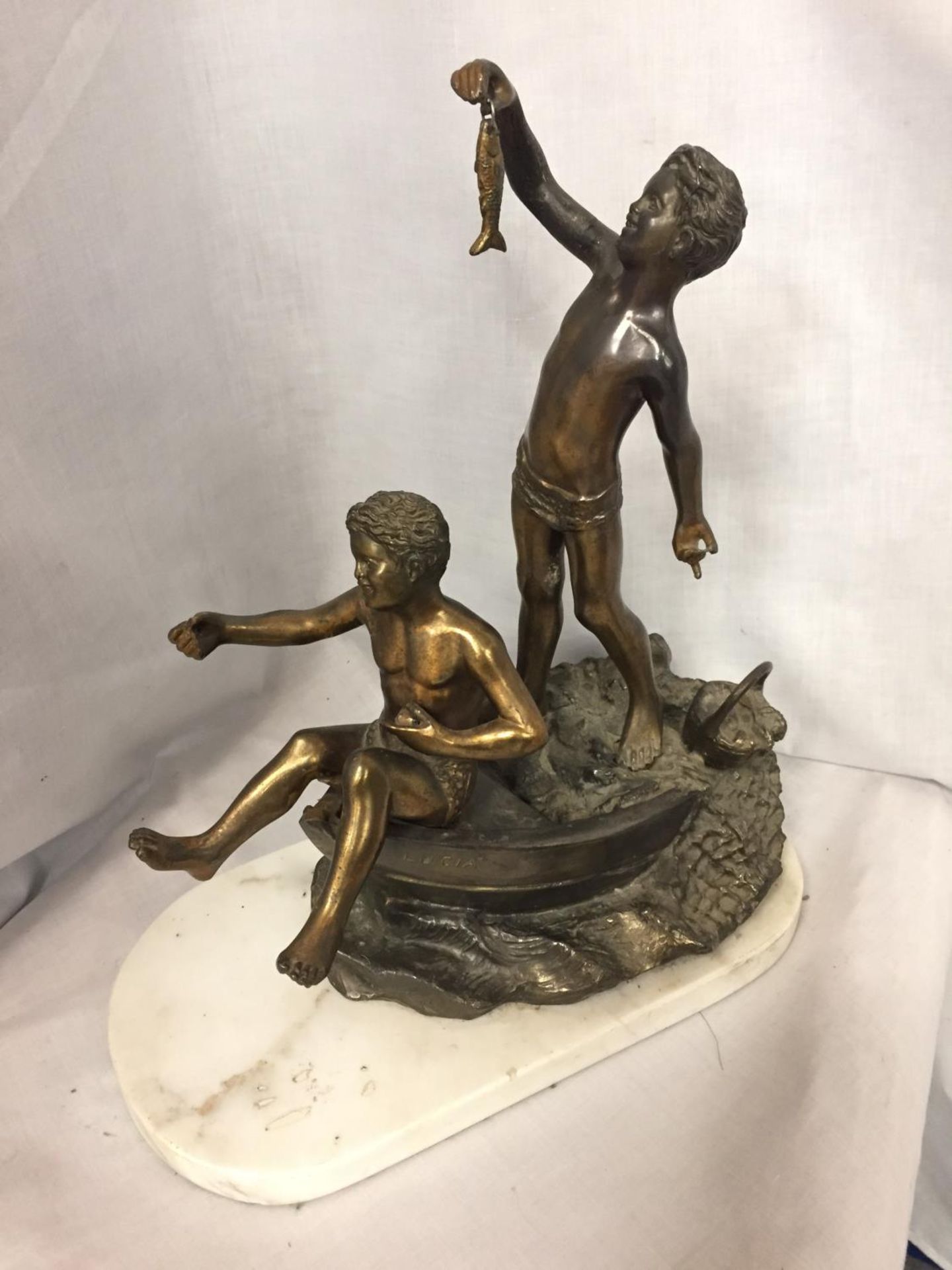 A SCULPTURE OF TWO BOYS IN A ROWING BOAT ON A MARBLE BASE