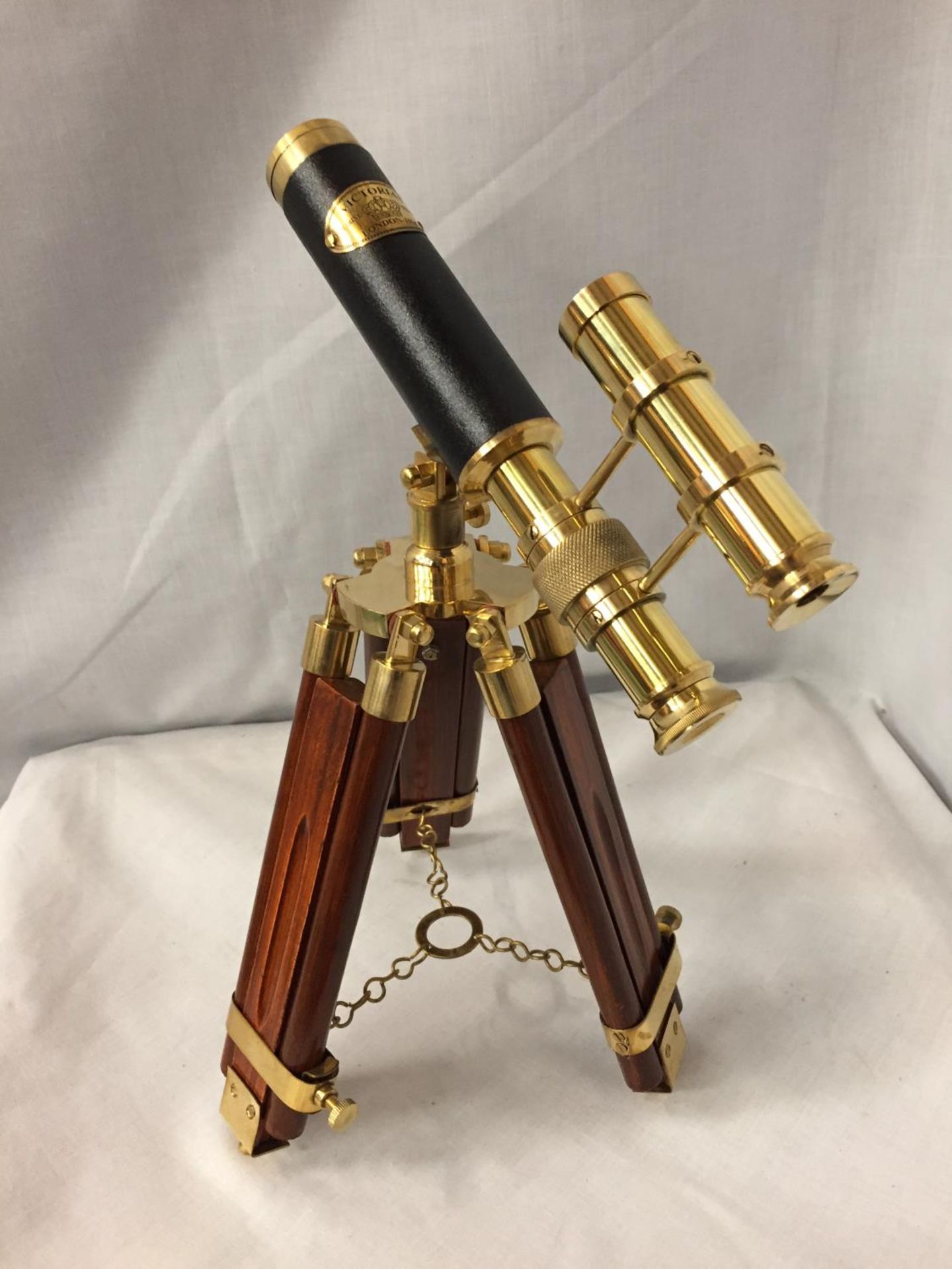 A BRASS AND LEATHER TELESCOPE ON A WOODEN TRIPOD STAND, 34CM HIGH