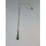 A 9 CARAT GOLD NECKLACE WITH A THREE IN LINE GREEN STONE PENDANT