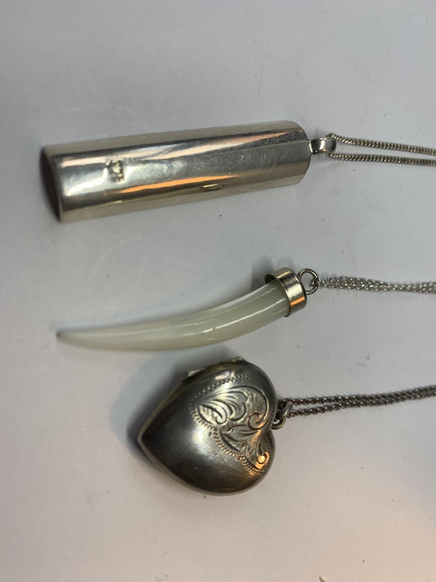 THREE SILVER NECKLACES WITH PENDANTS TO INCLUDE A HEART LOCKET, PEARLISED TOOTH AND A BAR WITH A - Image 2 of 2