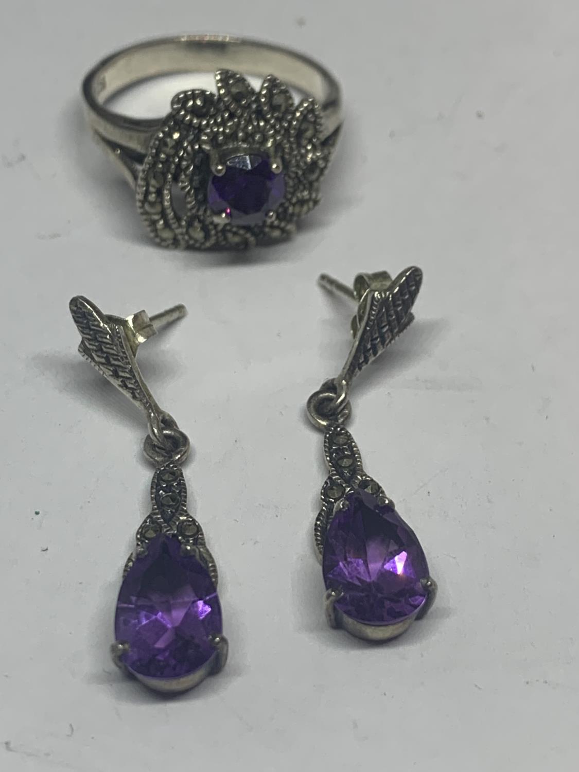 A SILVER MARCASITE AND PURPLE STONE RING WITH MATCHING EARRINGS IN A PRESENTATION BOX