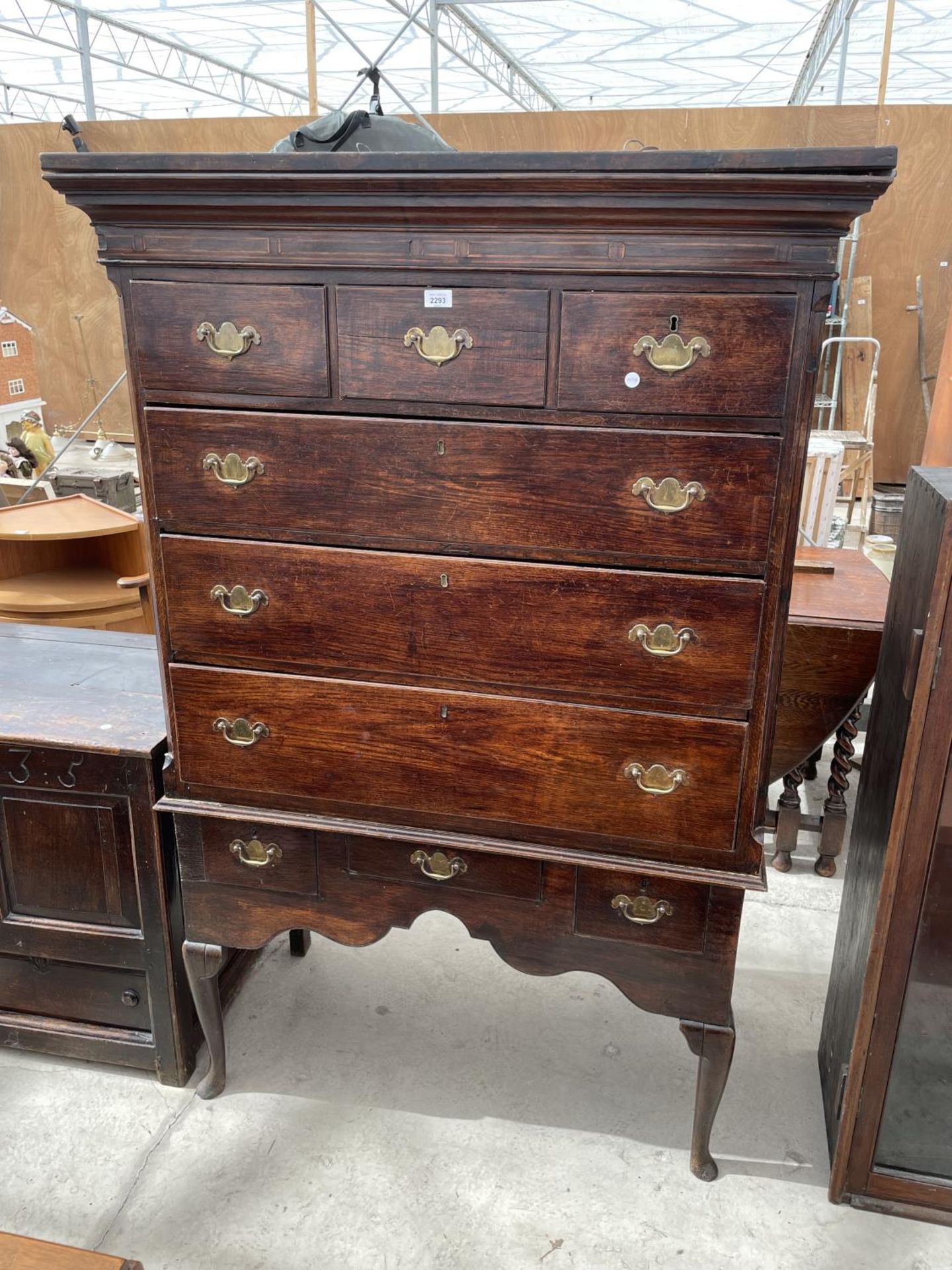A GEORGE III OAK CHEST ON STAND, THE BASE ON FRONT CABRIOLE LEGS, WITH THREE DRAWERS, THE UPPER