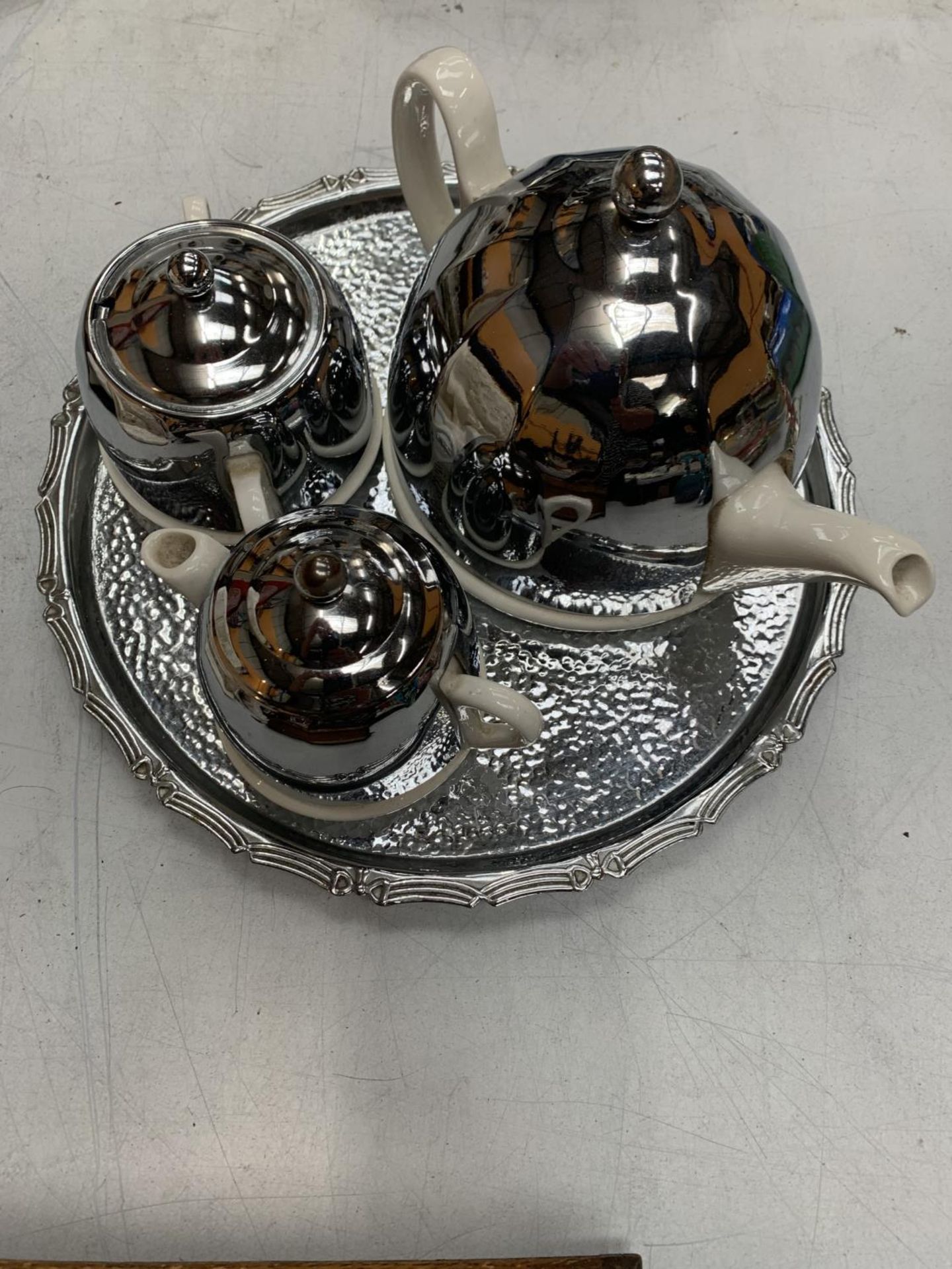 A RETRO STYLE SILVER PLATED AND CERAMIC TEAPOT, JUG AND SUGAR BOWL ON A PLATED TRAY