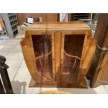 A WALNUT ART DECO STYLE CABINET WITH TWO GLAZED DOORS (AF TO TOP AND ONE PAIN REQUIRES REPLACING)
