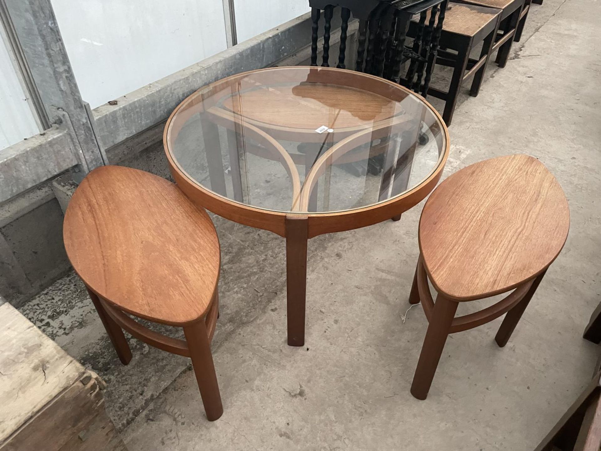 A RETRO TEAK CIRCULAR NEST OF FOUR TABLES WITH GLASS TOP AND THREE UNDER TABLES, OVAL IN SHAPE, - Image 4 of 7