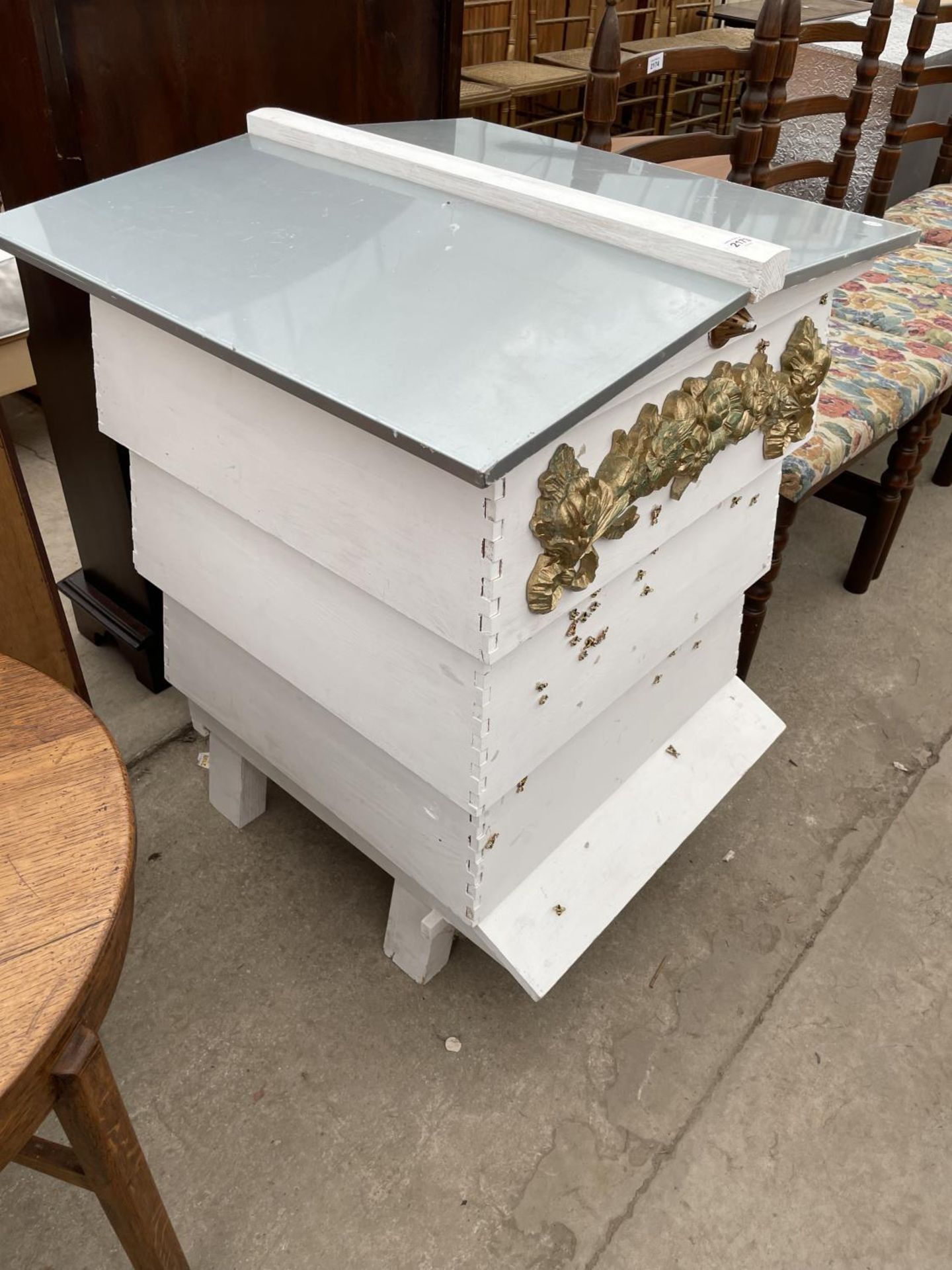 A FOUR TIER WHITE PAINTED FORMER BEEHIVE, DECORATED WITH BEES AND FLOWERS