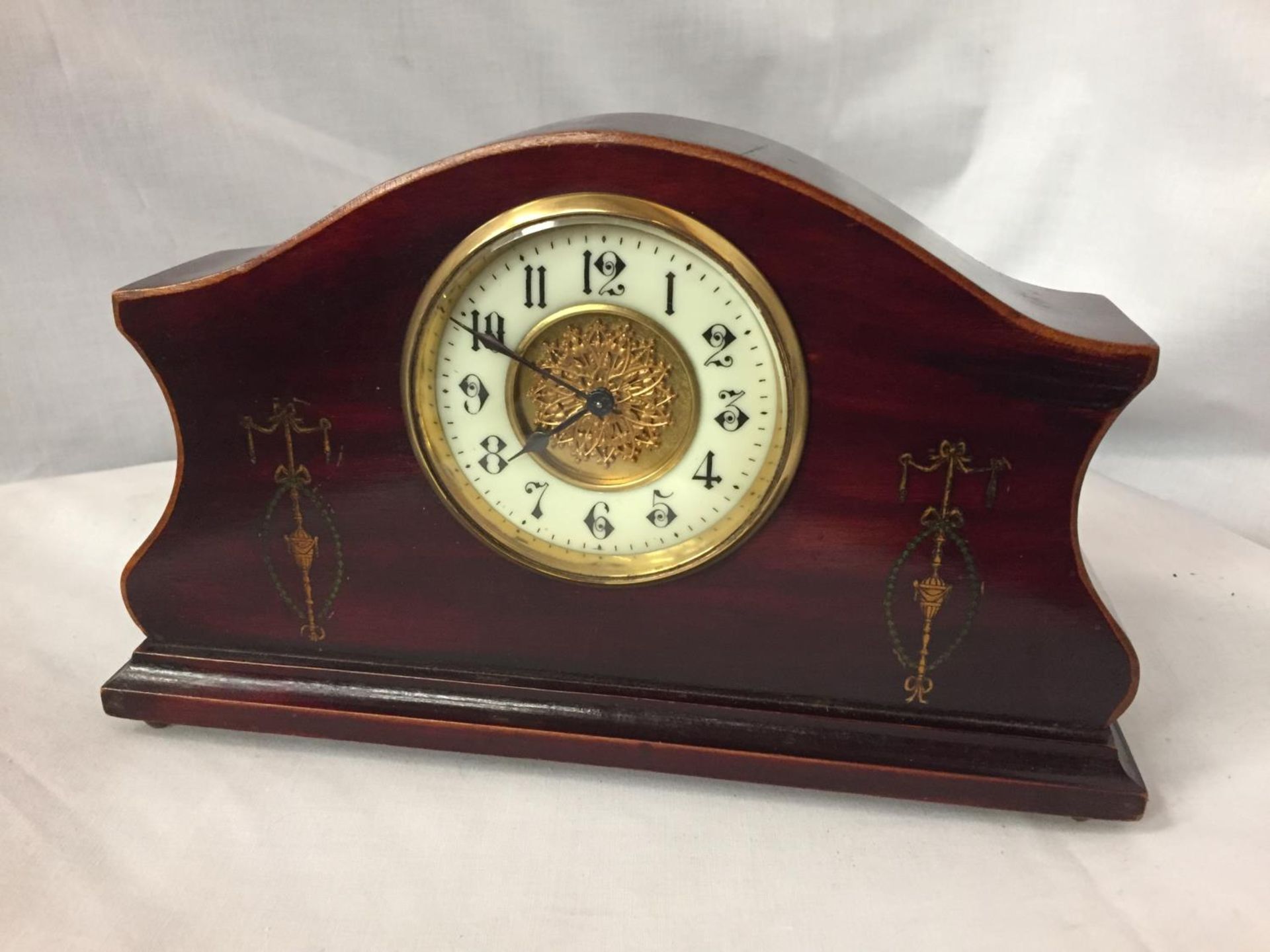 AN INLAID MAHOGANY MANTLE CLOCK WITH GILDED CENTRE FACE AND ENAMEL DIAL