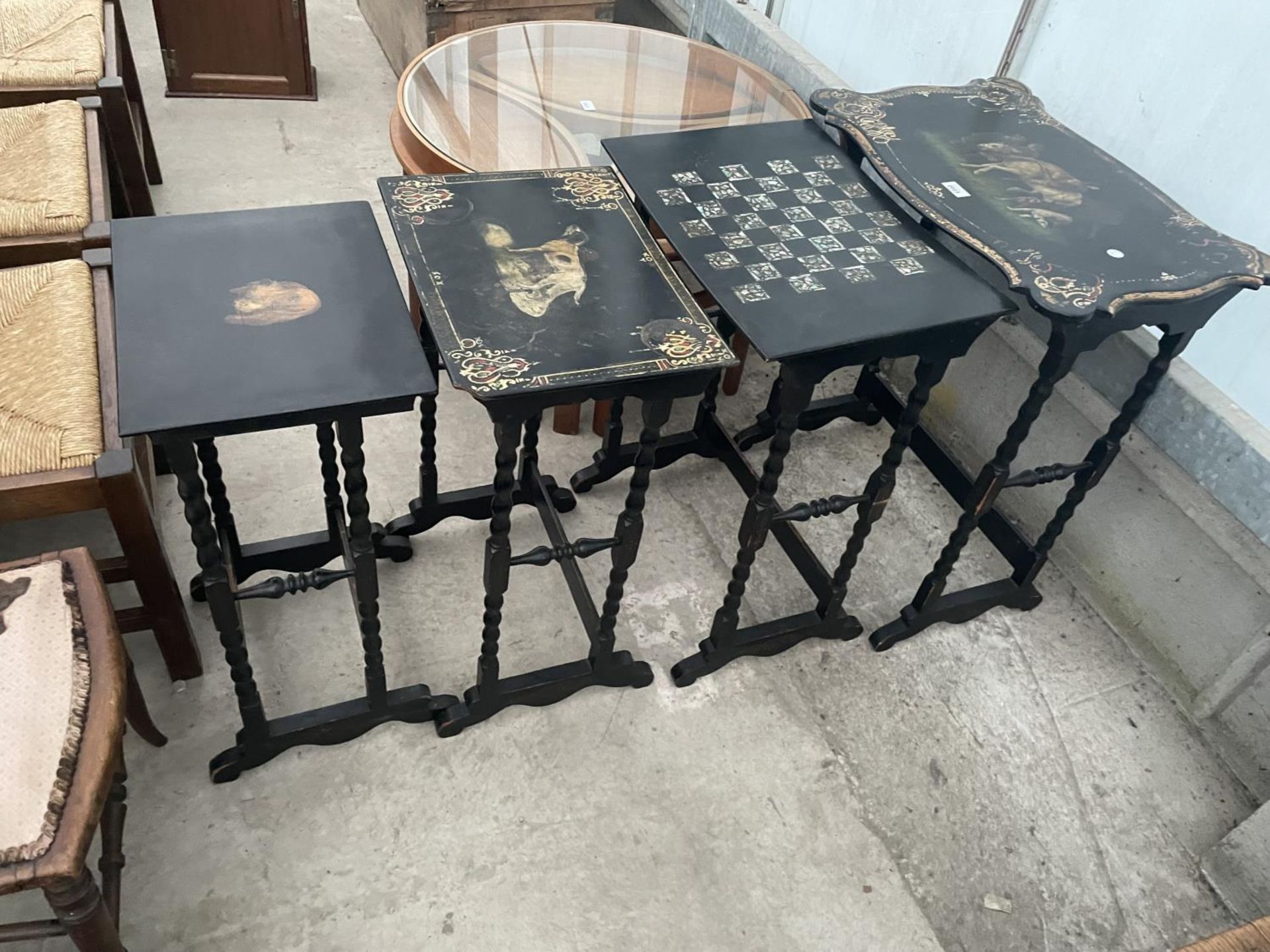 A NEST OF FOUR EBONISED AND PAPIER MACHE TABLES, THREE TABLES BEARING HUNTING IMAGE AND ONE WITH