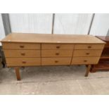 A RETRO SCHREIBER CHEST OF NINE DRAWERS, ON OPEN BASE, 58.5" WIDE, THE DRAWERS HAVING UNUSUAL