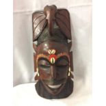 A CARVED WOODEN TRIBAL INSPIRED MASK WALL HANGING