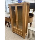 A MODERN OAK TWO DOOR DISPLAY CABINET WITH TWO DRAWERS TO THE BASE, 37" WIDE (LACKING SHELVES)