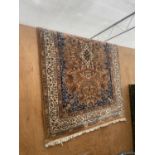 AN ORANGE PATTERNED WOOL RUG WITH TASSELED EDGE (195CM X 127CM)