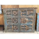 A HEAVILY CARVED AND DECORATIVE MOROCCAN DOOR WITH METAL BANDING AND STUD WORK, TO INCLUDE METAL