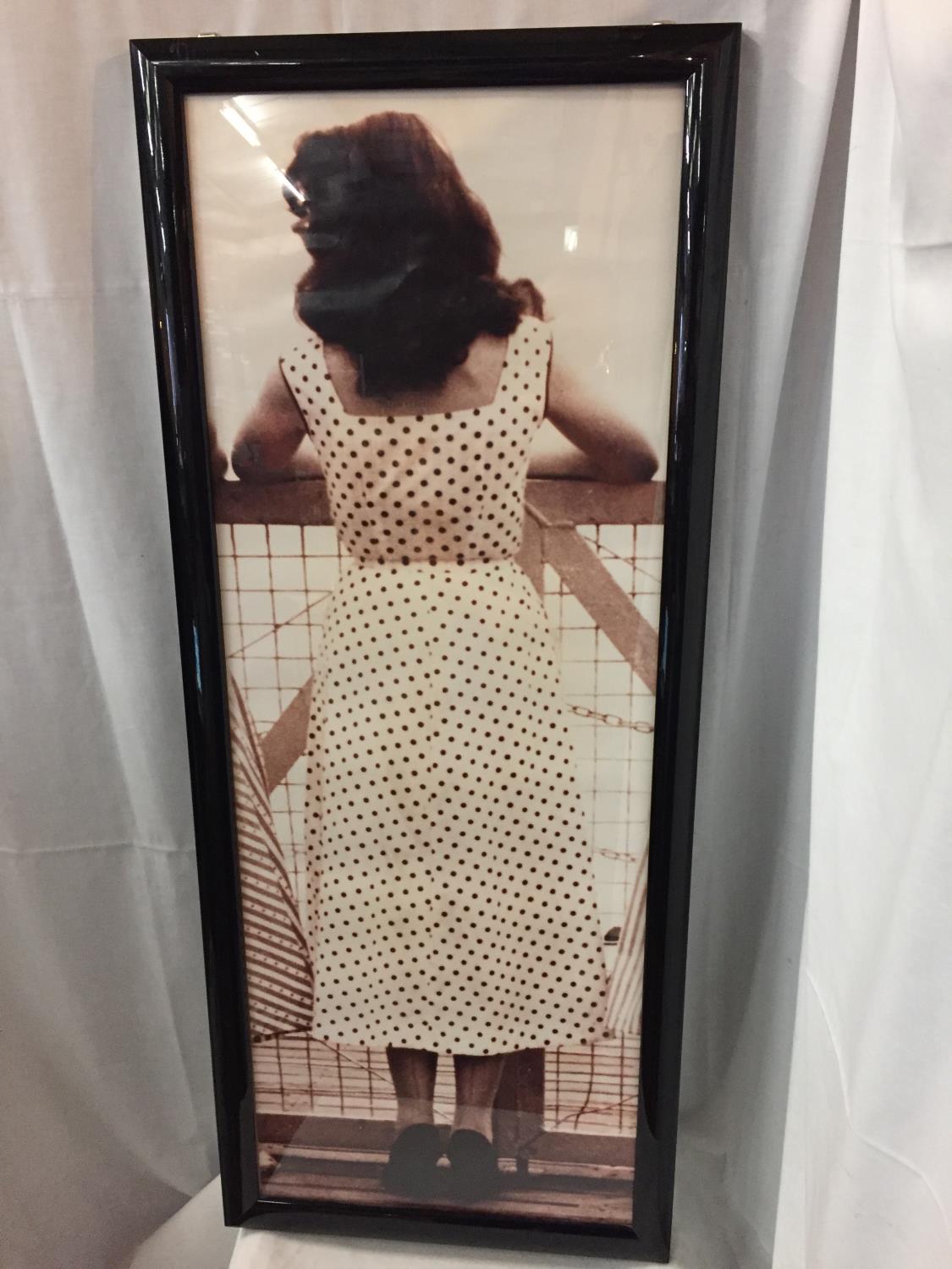 A LARGE BLACK FRAMED ORIGINAL KODAK PRINT OF A 1940'S LADY IN A POLKA DOT DRESS AND SEAMED STOCKINGS