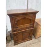 AN OAK OLD CHARM STYLE COCKTAIL CABINET WITH DROP-DOWN FRONT, SINGLE DRAWER AND CUPBOARDS TO THE