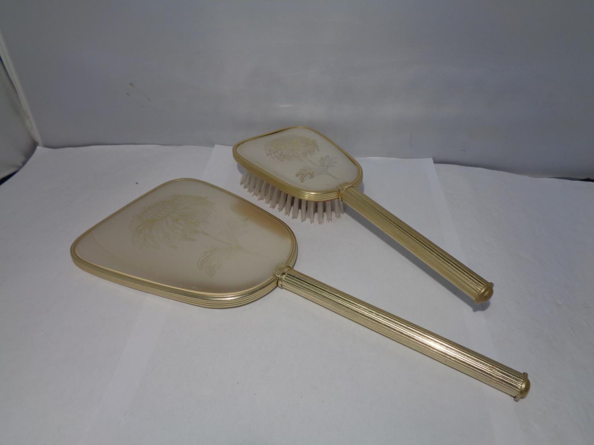 A DRESSING TABLE SET TO INCLUDE A HAND MIRROR AND MATCHING BRUSH