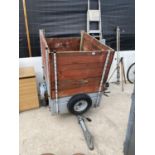 A SMALL CAR TRAILER WITH WOODEN EXTENDED SIDES
