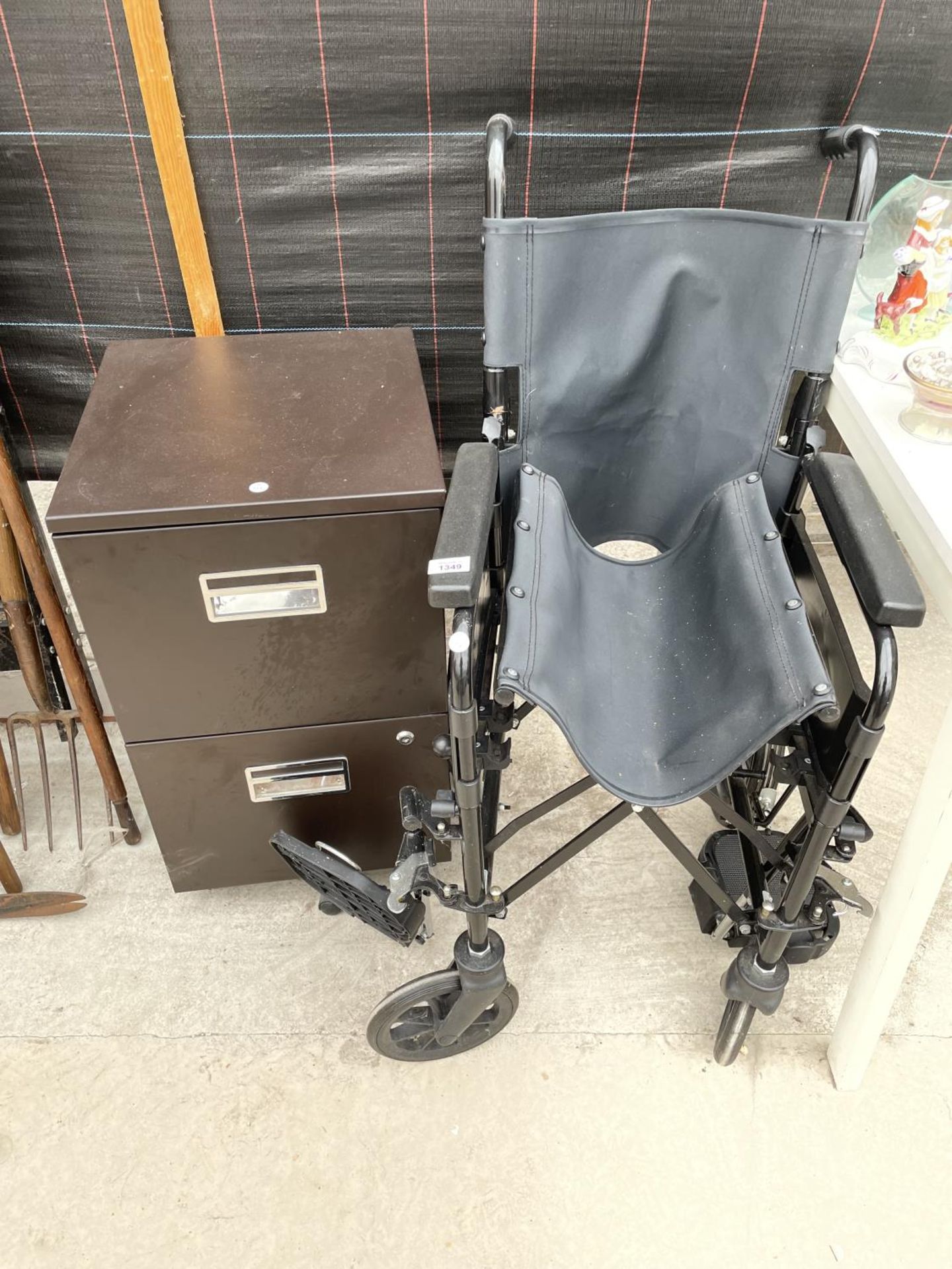 A WHEEL CHAIR AND A TWO DRAWER METAL FILING CABINET