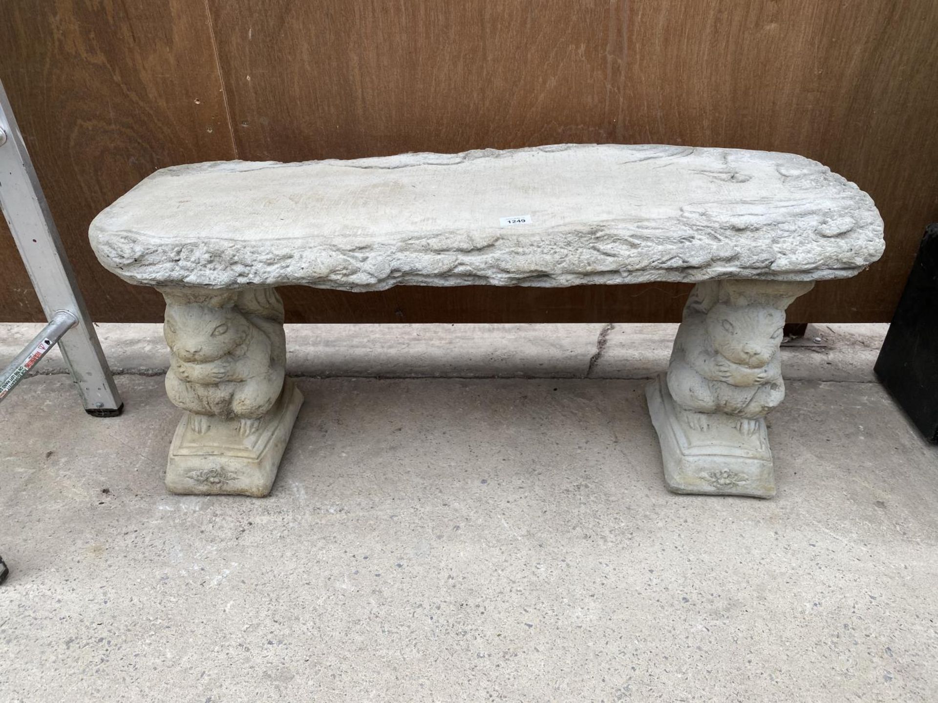 A STONE EFFECT GARDEN BENCH WITH SQUIRREL PEDASTEL BASE