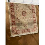 A CREAM AND RED FRINGED PATTERNED RUG