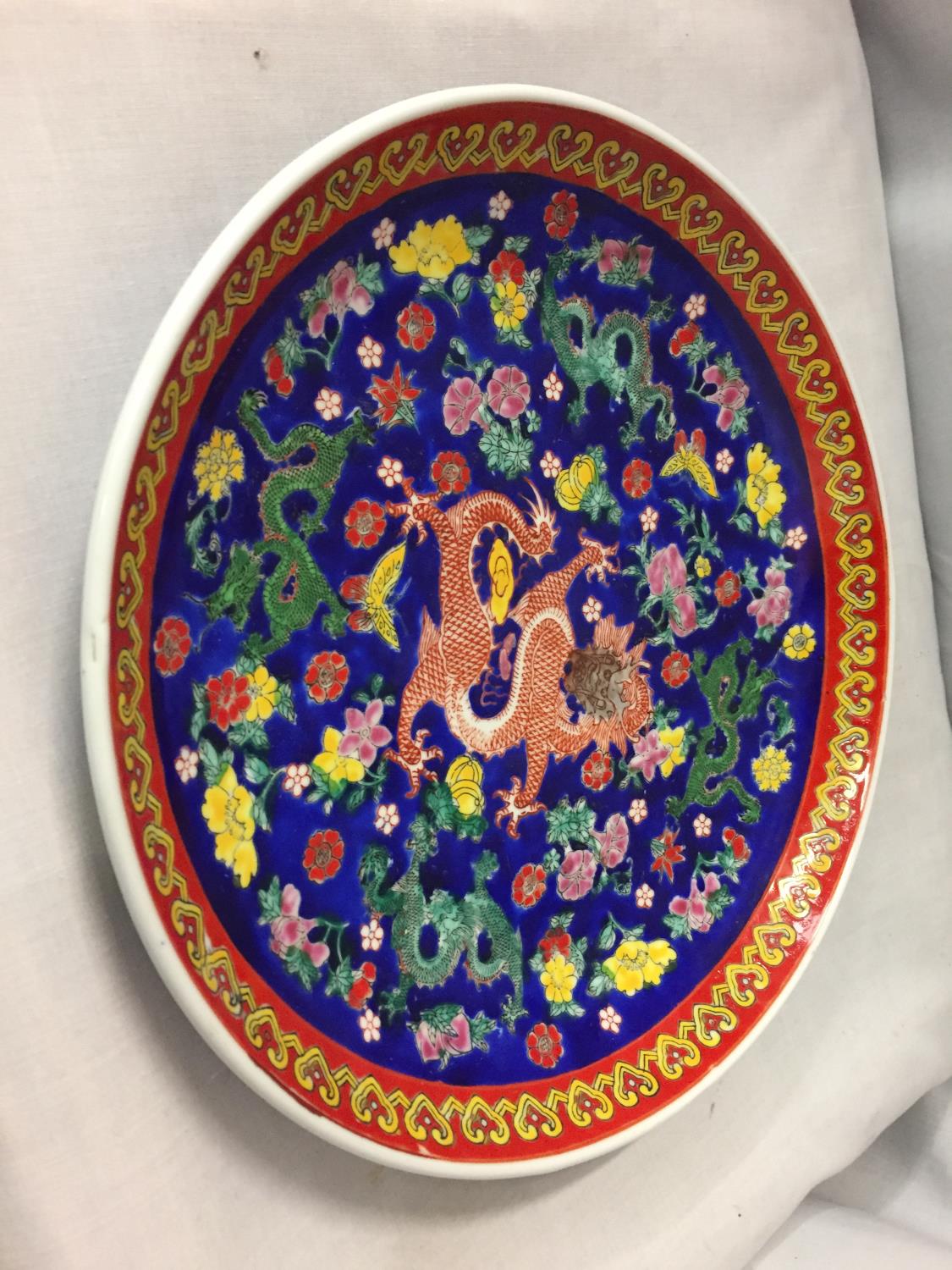 A DECORATIVE ORIENTAL CHARGER WITH A DRAGON DESIGN