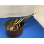 A SET OF NINE COPPER GRADUATED PANS WITH BRASS HANDLES