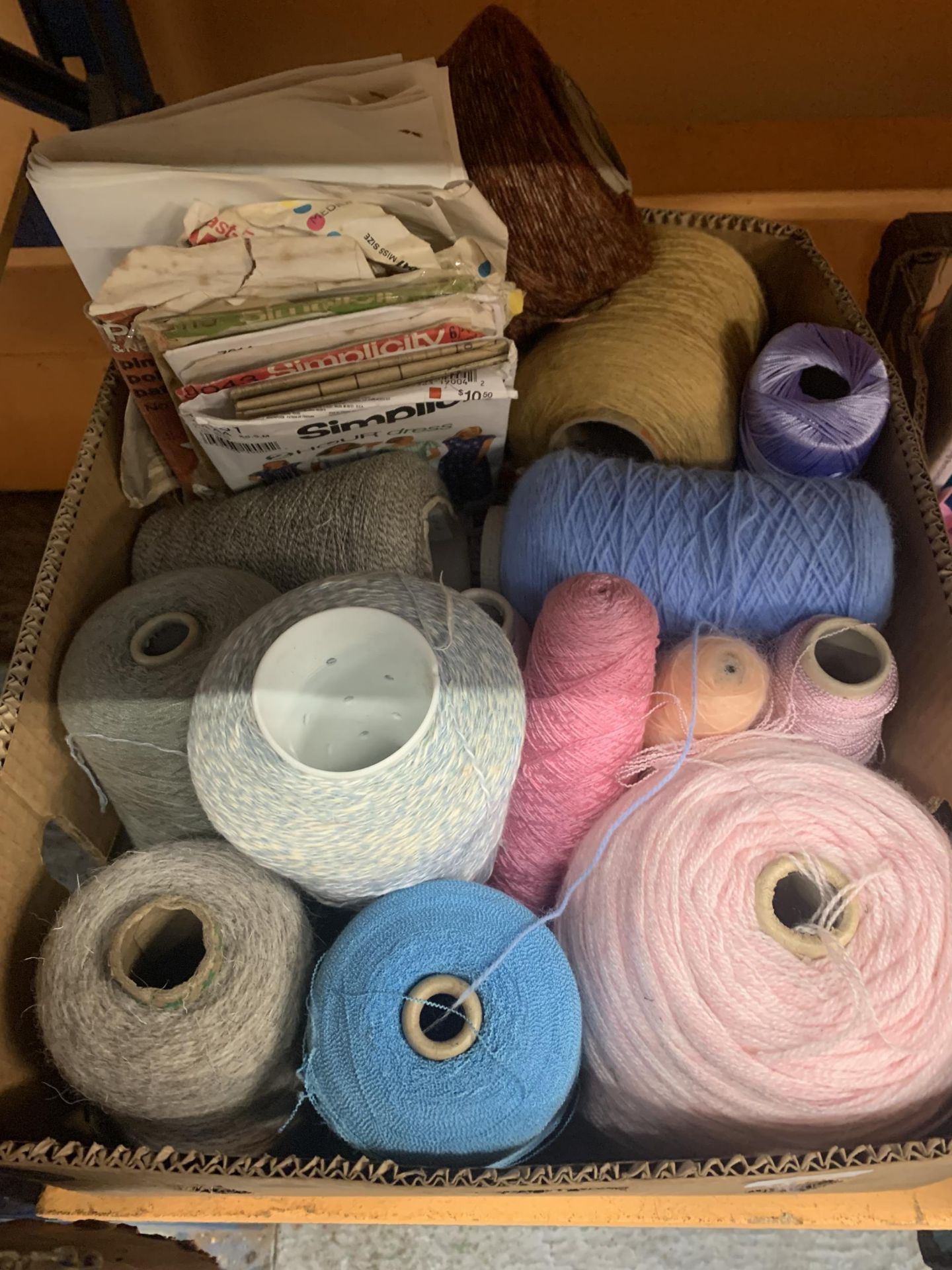 A SELECTION OF SPOOLED YARNS AND SEVERAL CLOTHING PATTERNS