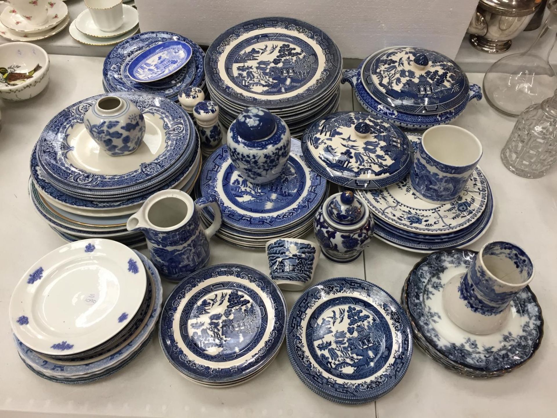 A LARGE SELECTION OF MAINLY, BLUE WILLOW PATTERN CHINA PLATES ALONG WITH A CRUET SET AND GINGER JARS