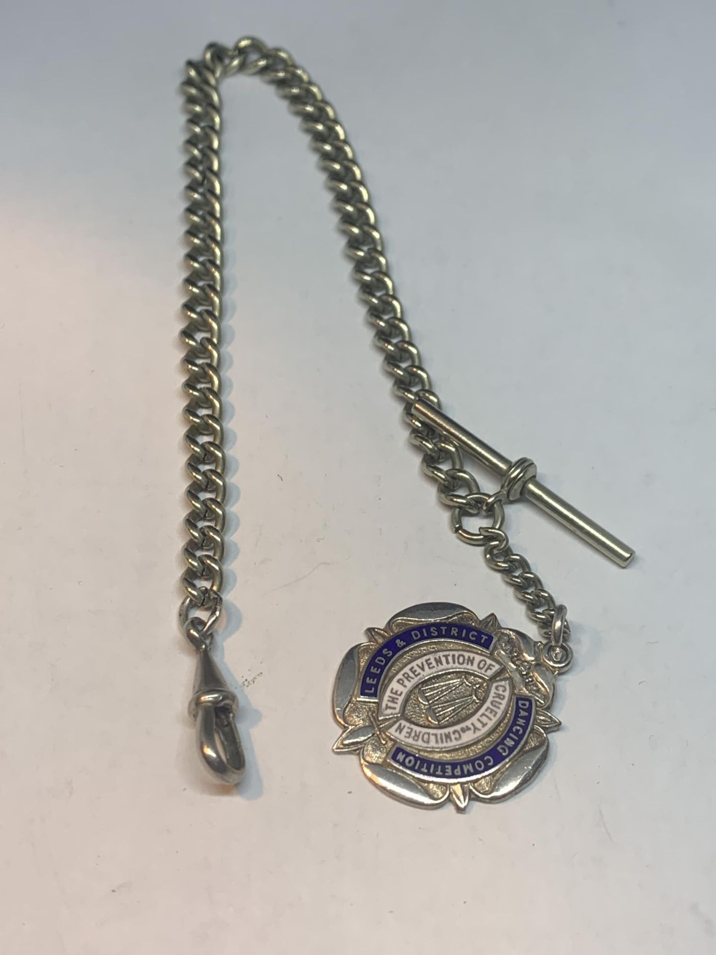 A WHITE METAL HALF ALBERT WATCH CHAIN WITH A LEEDS AND DISTRICT DANCING COMPETITION FOB