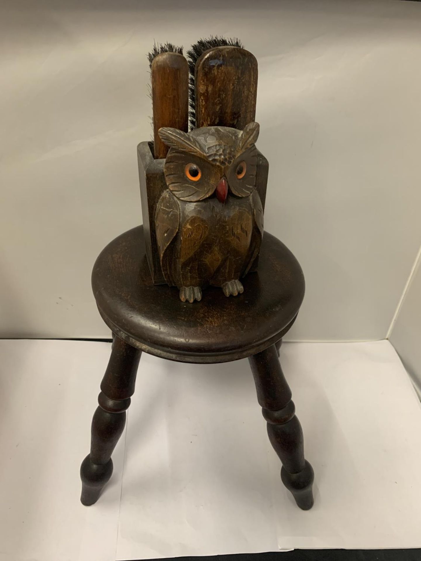 A SMALL OAK STOOL HEIGHT 24CM WITH A WOODEN OWL DESIGN WALL BOX CONTAINING SHOE CLEANING BRUSHES