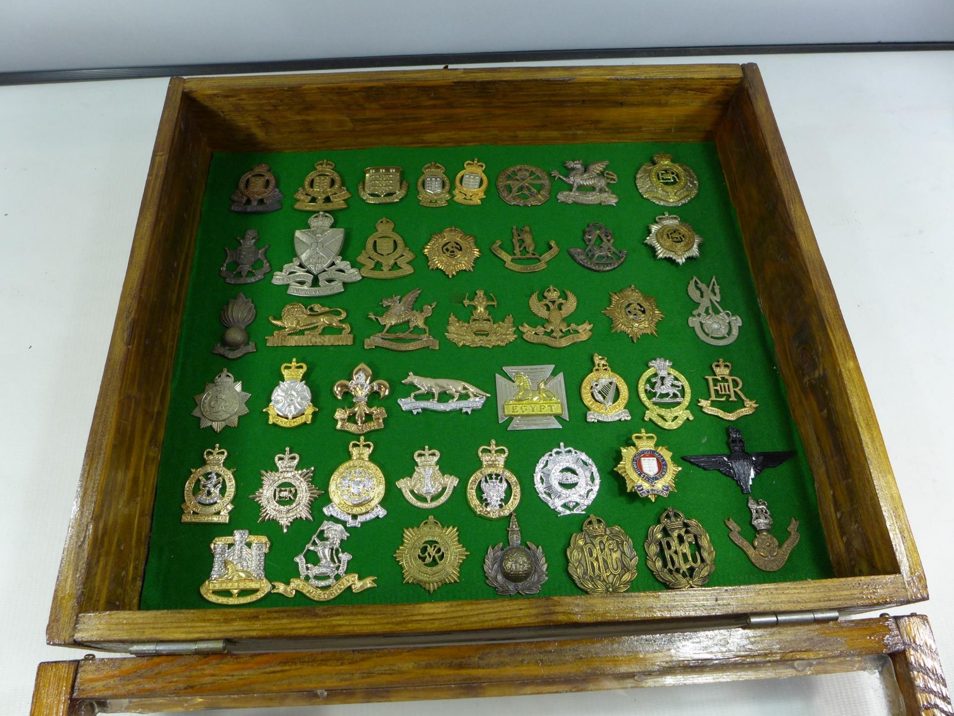 A GLAZED DISPLAY CASE CONTAINING FORTY FIVE BRITISH MILITARY BADGES, 34CM X 39CM
