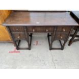 AN OAK JACOBEAN STYLE DRESSING TABLE ON TURNED LEGS ENCASING FIVE DRAWERS 46" WIDE