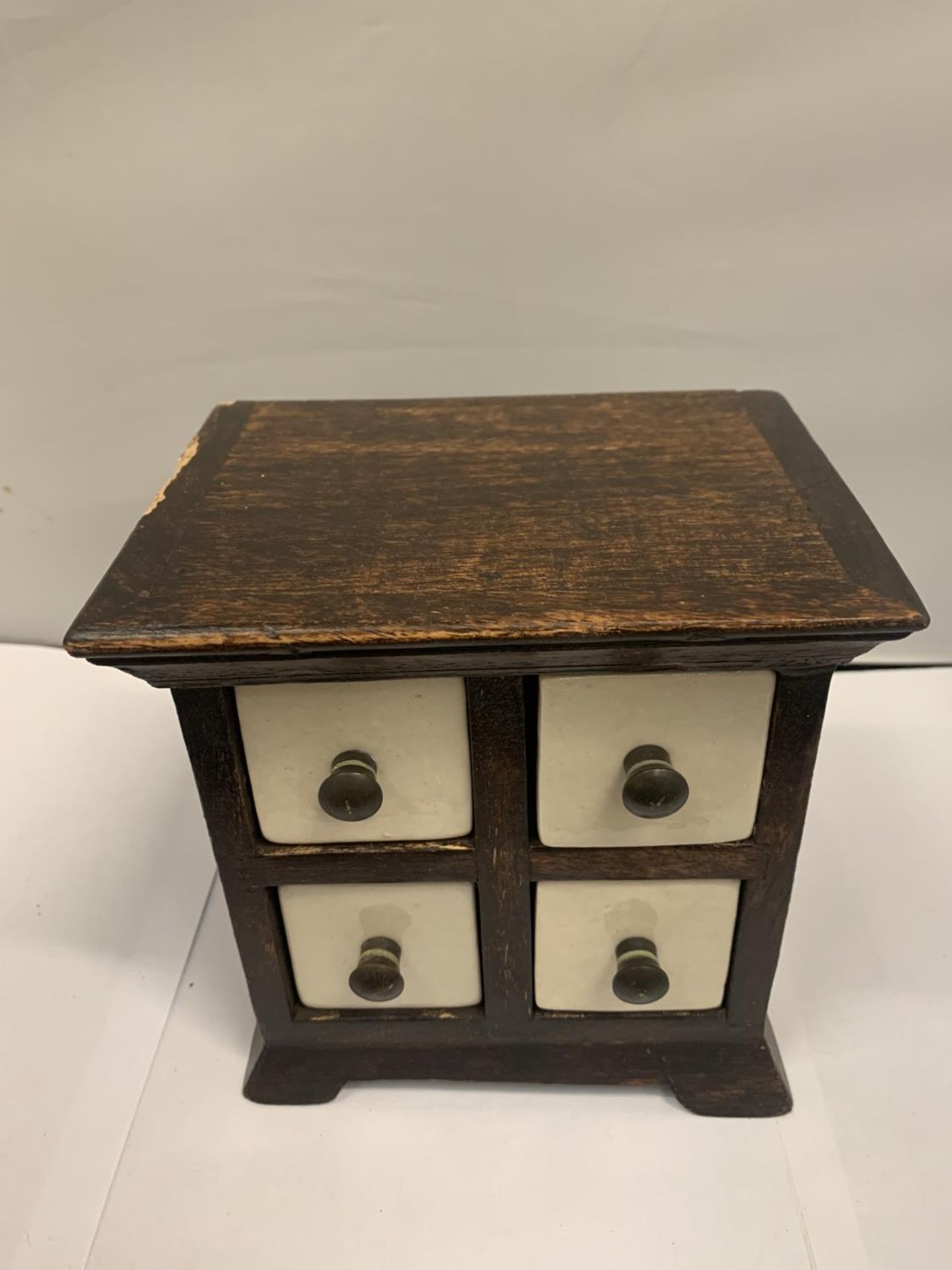 A MINATURE WOODEN CHEST WITH FOUR GLAZED CERAMIC DRAWERS