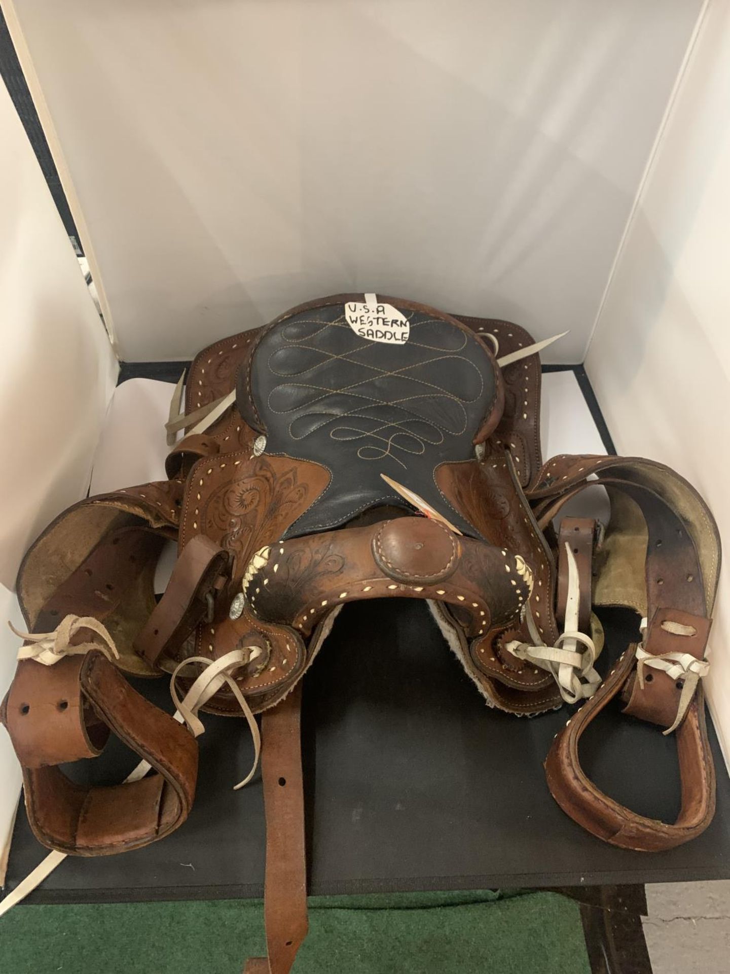 A TAN AND BLACK LEATHER U.S.A. WESTERN SADDLE WITH DECORATIVE DESIGNS AND STITCHING TOGETHER WITH