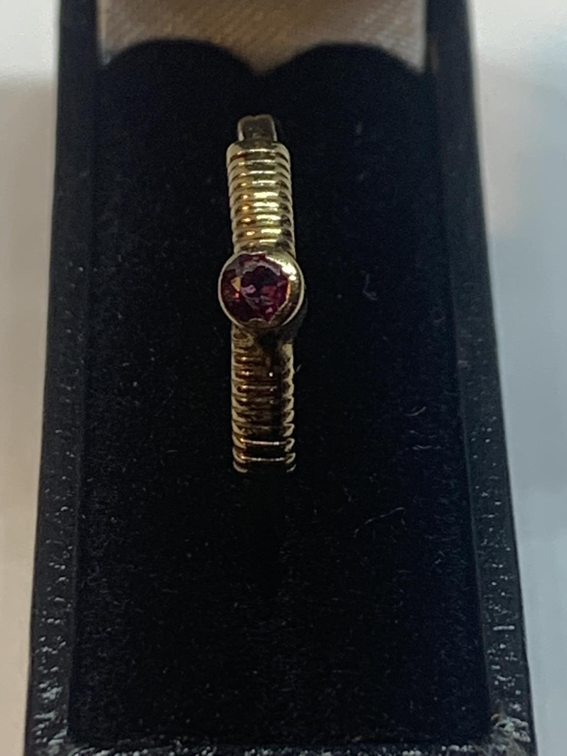 A 9 CARAT GOLD RING WITH A SINGLE RAISED PURPLE STONE AND CROSS BANDING TO THE SHOULDERS - Bild 2 aus 5