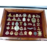 A GLAZED DISPLAY CASE CONTAINING THIRTY NINE BRITISH ARMY CAP BADGES, 34CM X 48CM