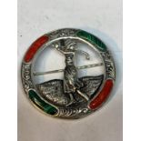 A MARKED SILVER BROOCH WITH GREEN AND RED STONES DEPICTING A LADY GOLFER