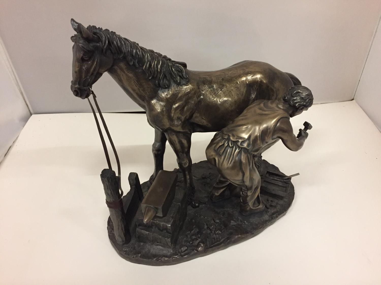 A RESIN FIGURINE OF A HORSE AND FARRIER HEIGHT 26CM