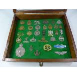 A GLAZED DISPLAY CASE CONTAINING THIRTY TWO BRITISH ARMY CAP BADGES, 34CM X 40CM