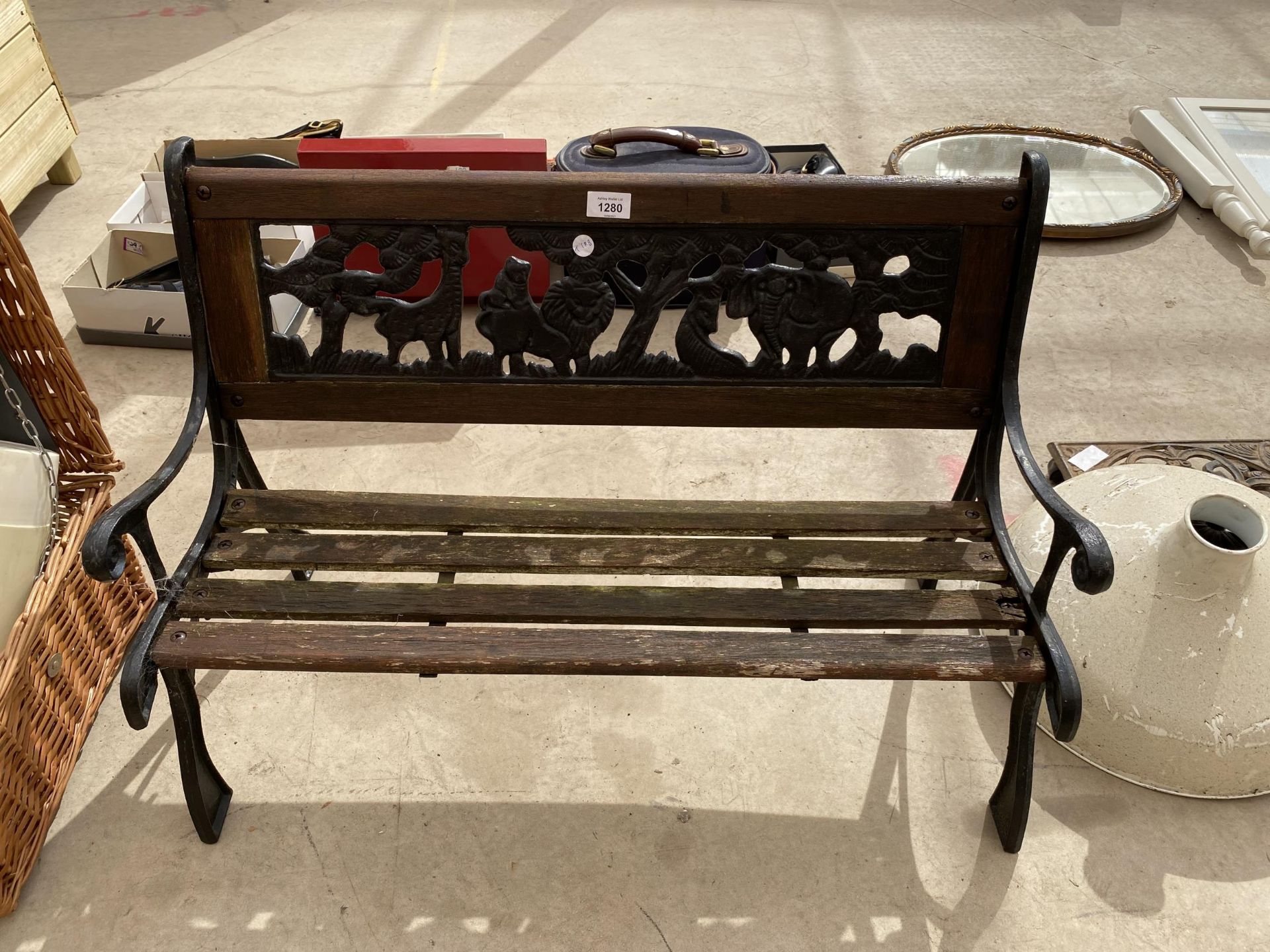 A SMALL CHILDRENS GARDEN BENCH WITH CAST BENCH ENDS AND A CAST BACK DEPICTING A SAFARI SCENE