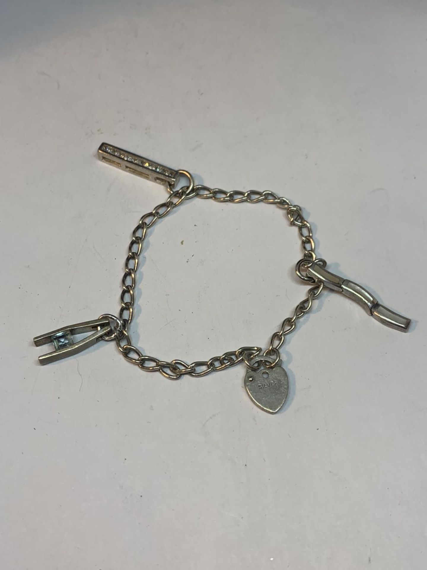 A SILVER BRACELET WITH THREE CHARMS AND A HEART PADLOCK