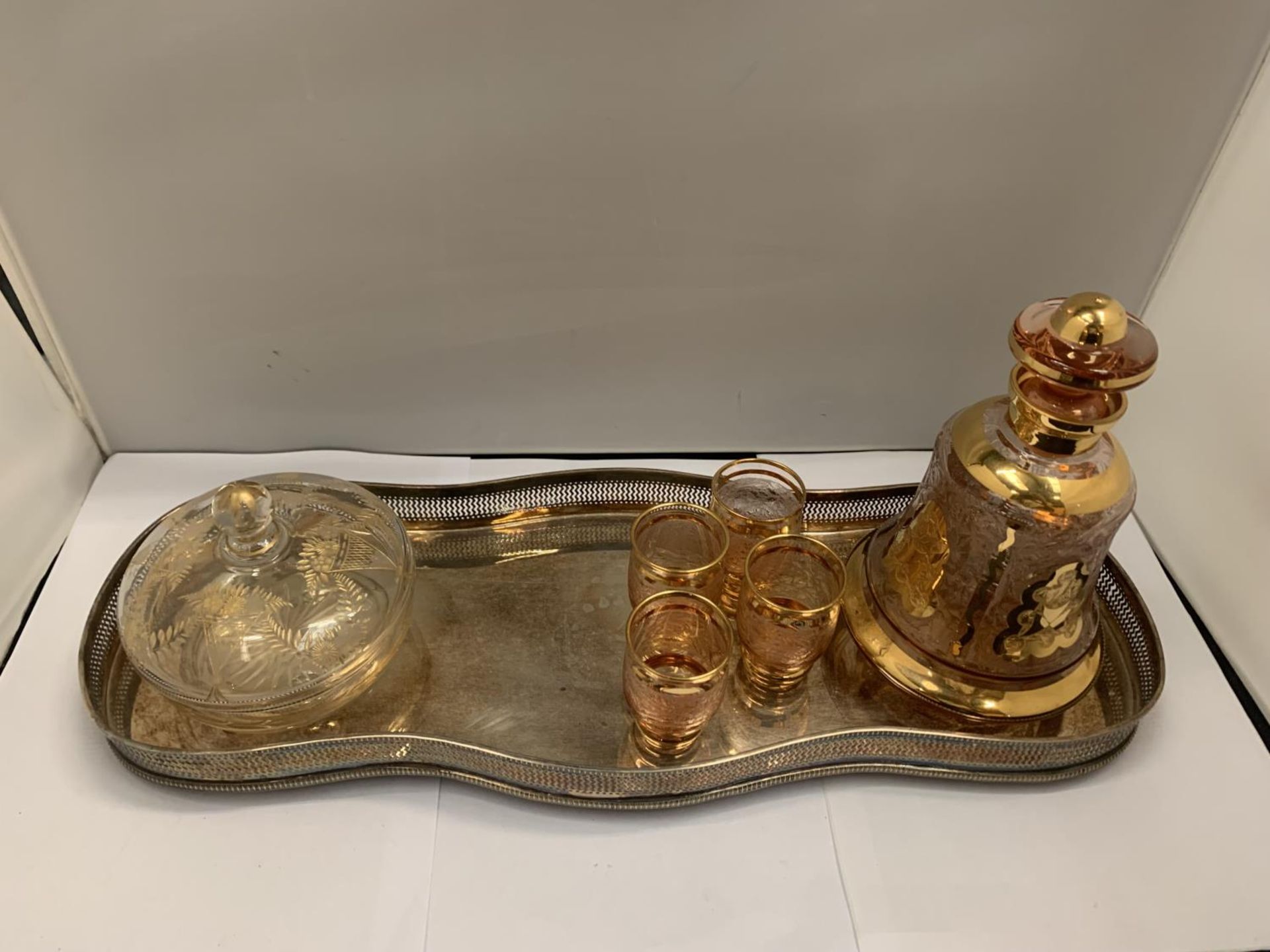 A SILVER PLATED TRAY WITH ORNATE DECANTER, FOUR GLASSES AND A LIDDED JAR