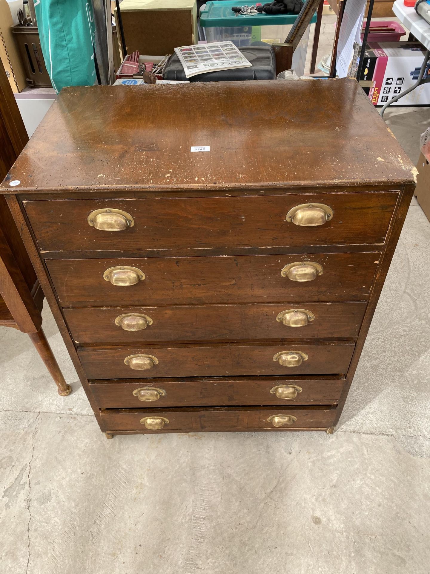 AN EARLY 20TH CENTURY STAINED PINE CHEST OF SIX DRAWERS WITH BRASS SCOOP HANDLES