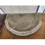 AN OVAL CREAM PATTERENED FRINGED RUG