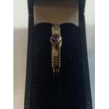 A 9 CARAT GOLD RING WITH A SINGLE RAISED PURPLE STONE AND CROSS BANDING TO THE SHOULDERS