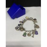 A SILVER CHARM BRACELET WITH THIRTEEN CHARMS TO INCLUDE A HORSE, RIDING HAT, DRAGON, APPLE ETC IN